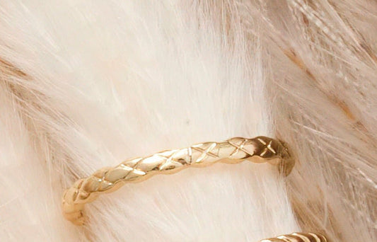 Dainty gold ring with cross design etched into the surface.