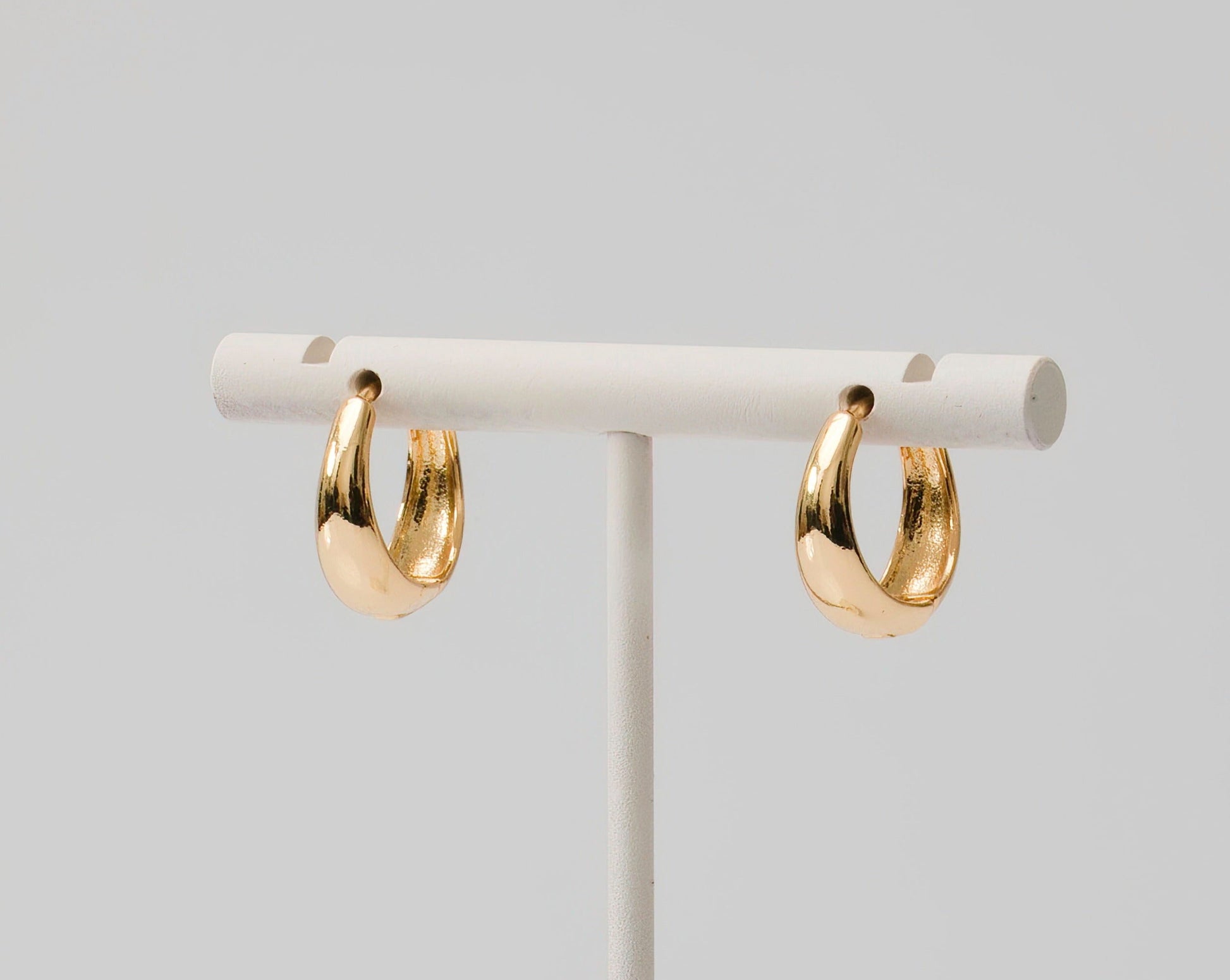 Gold huggie earrings dome shaped. Thin at top and thicker at bottom.