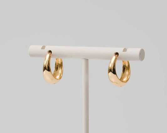 Gold huggie earrings dome shaped. Thin at top and thicker at bottom.