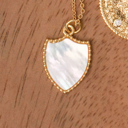 White shell shield shaped pendant on gold filled base with mini gold spheres surrounding pendant. With a 16" or 18.5 inch gold filled rolo chain